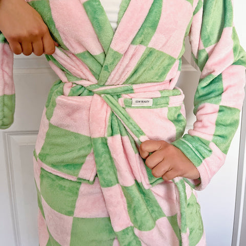 Person wearing a pink and green checkered robe with a brand label.